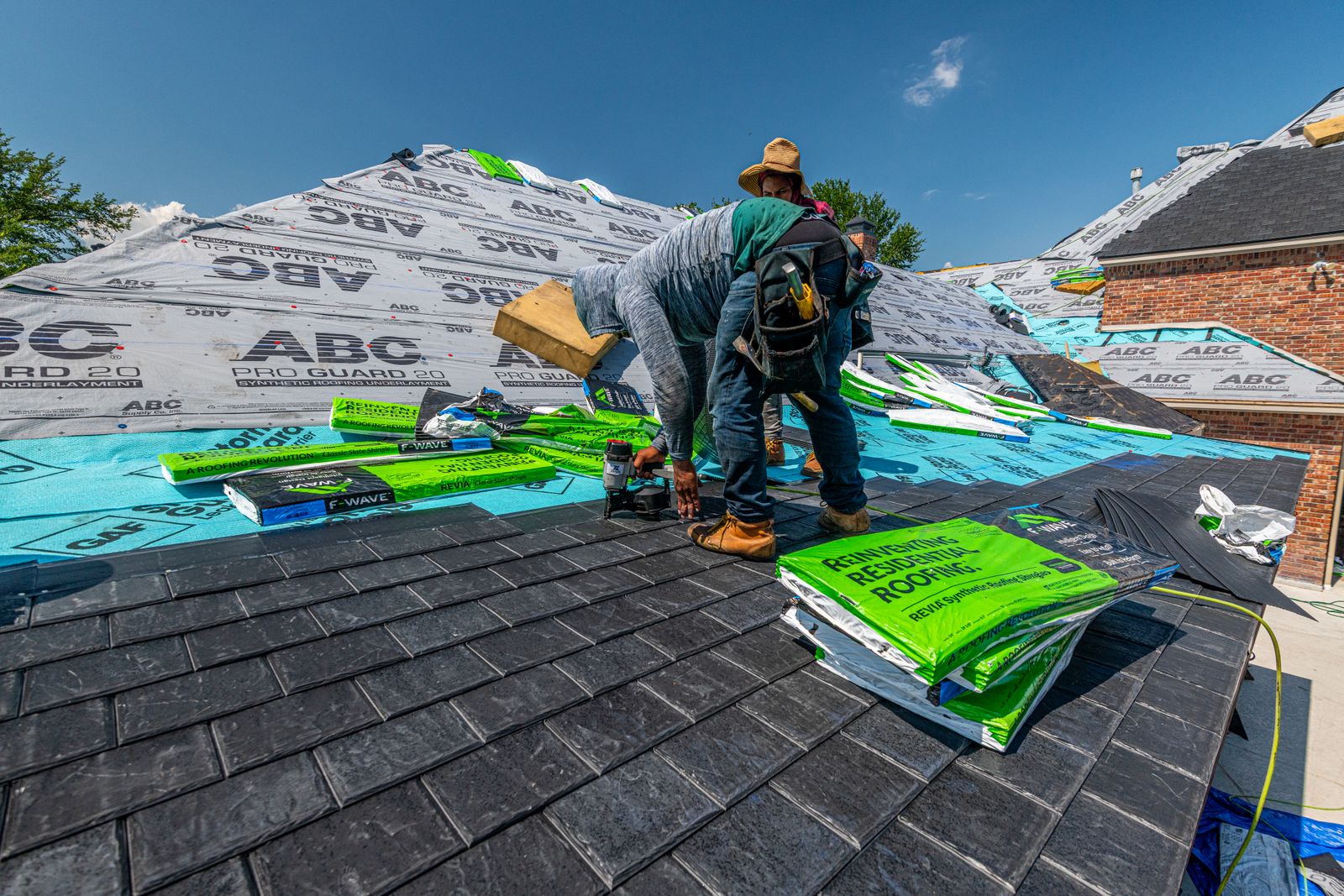 The crew rolling out synthetic underlayment over a freshly stripped deck