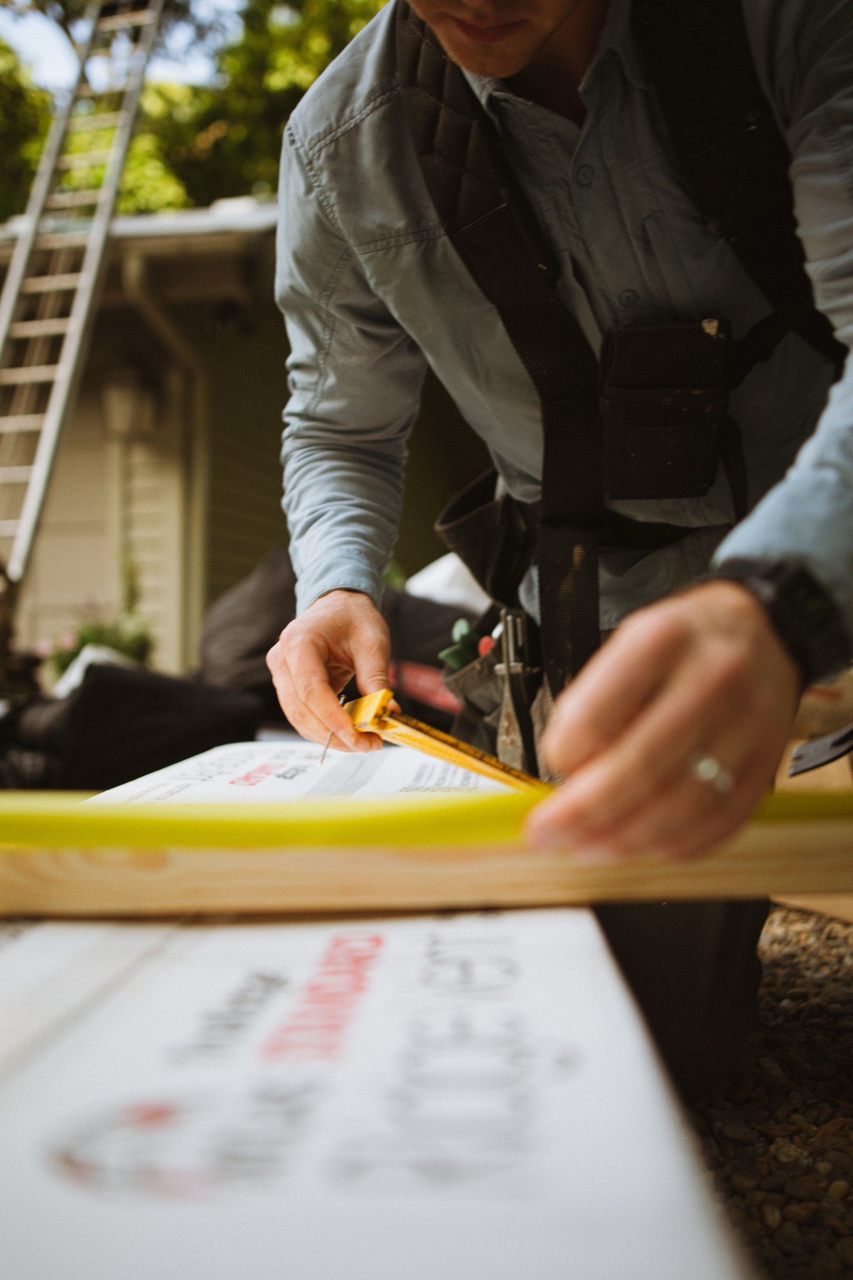 A roofer’s hands running a tape measure along a box of ridge vent