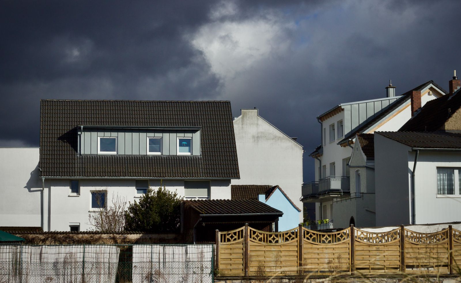 A dark storm front moving over a row of houses