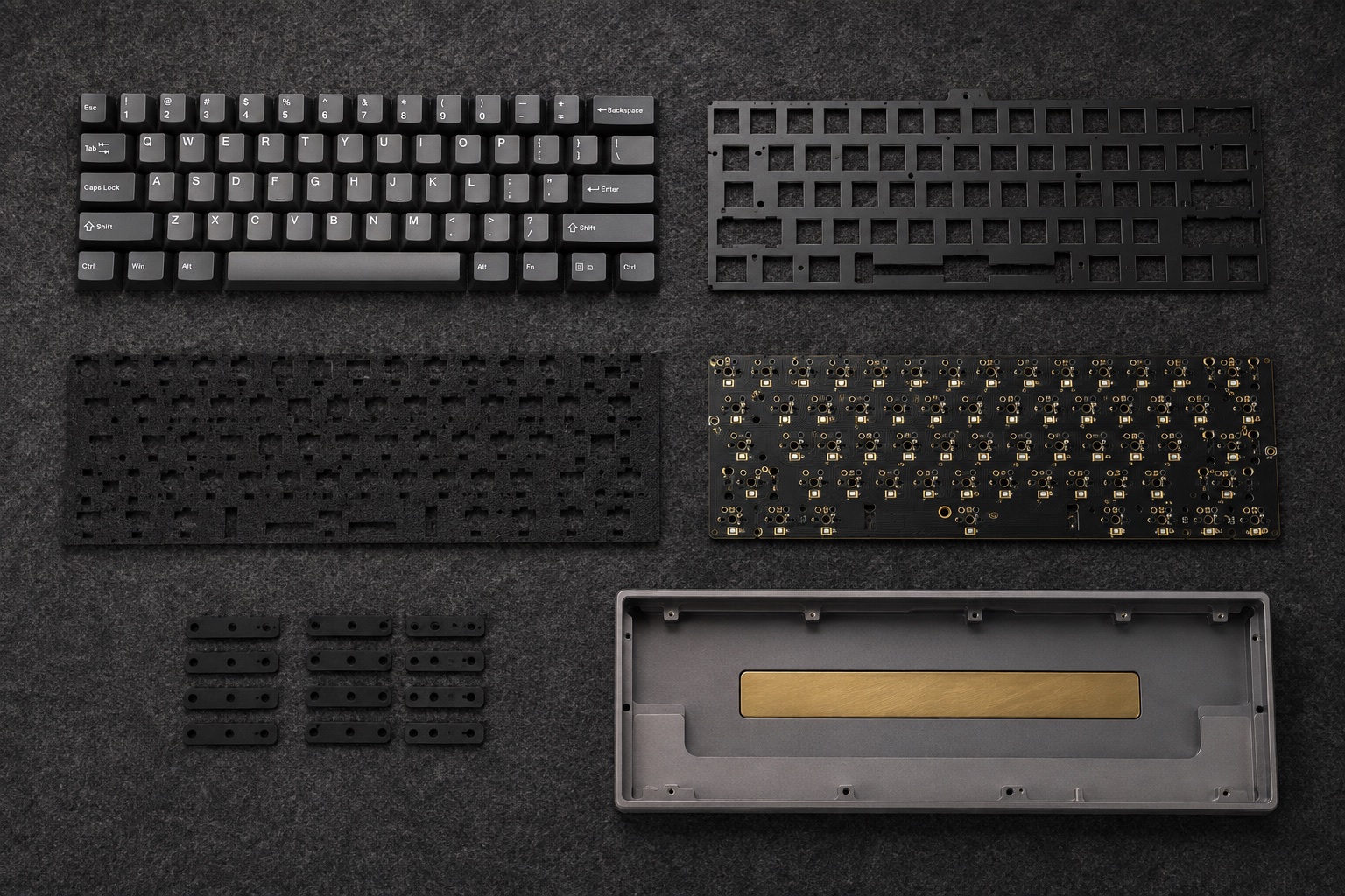 A disassembled Sable keyboard: graphite keycaps, switch plate, acoustic foam, circuit board, gasket tabs, and a machined aluminium case arranged on a dark workbench.