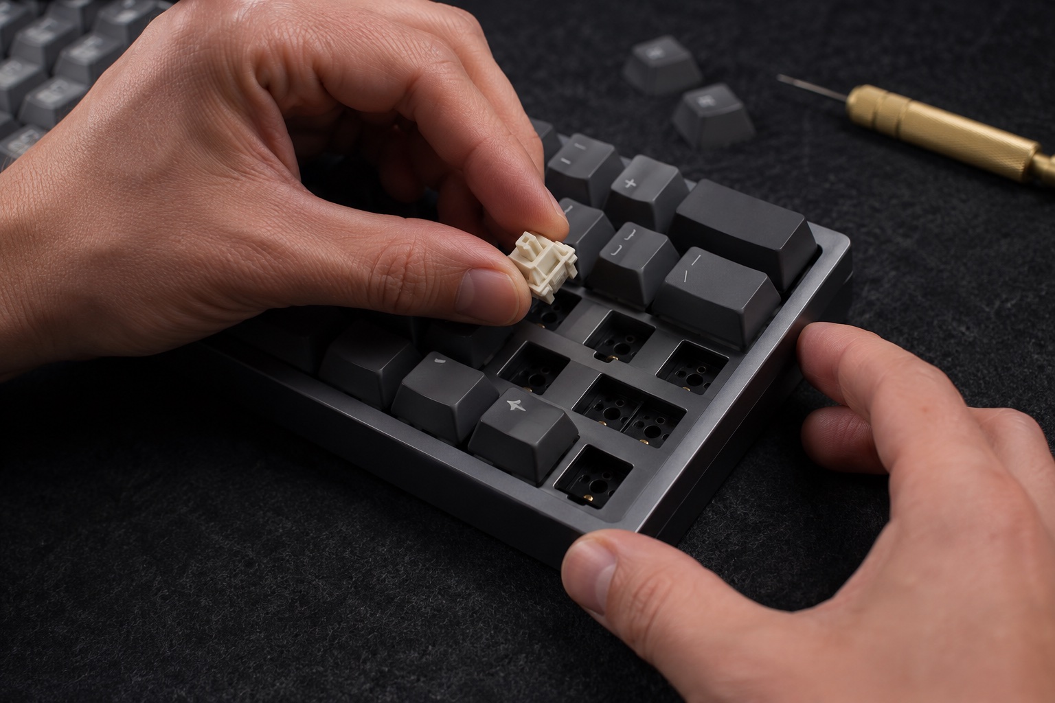 A technician carefully seats a mechanical switch in a Sable keyboard on a felt-covered workbench.