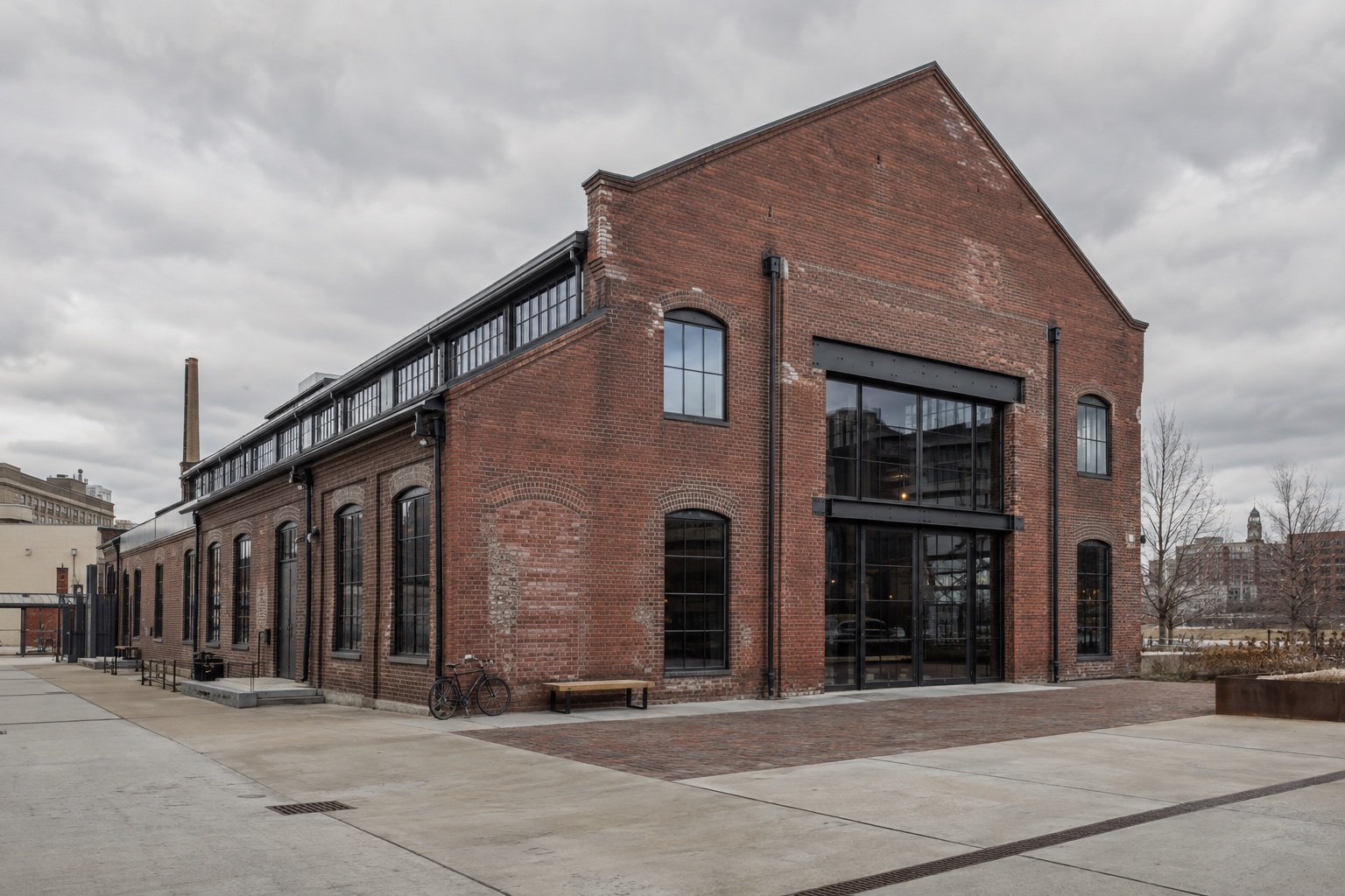 A restored brick industrial building with tall windows, retained masonry and a contemporary steel-framed entrance.